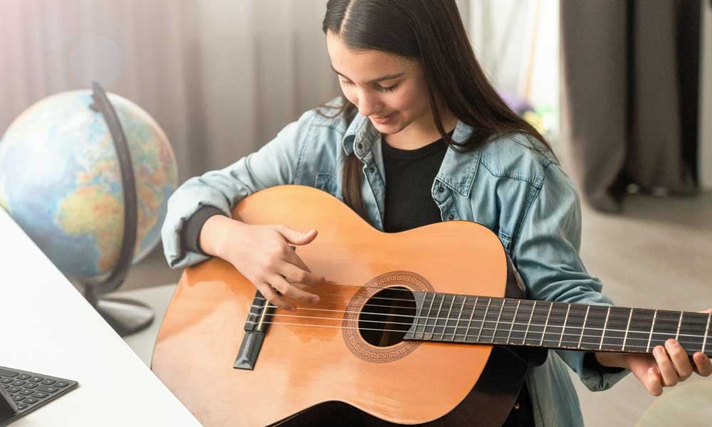 FUNDAÇÃO ROGE: jovem tocando violão nas atividades extracurriculares na escola